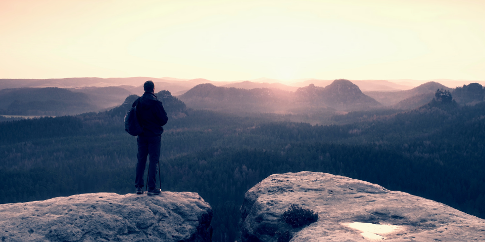 Lonely at the Top_980x490 Man standing alone on top of a mountain
